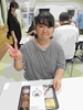 舎生がお弁当を前に笑顔でピースサインをしているところ①