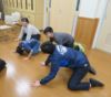 舎生と職員が床に手をついて「カエルのポーズ」をしているところ