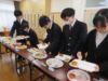 舎生が机に並んでいる食事をお皿にとっているところ