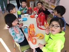 テーブルと６人の幼児が囲み、ぜんざいを食べる。