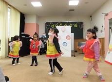 足を交差させて、レットイットゴーを踊る、赤と黄色の衣装を着た幼児４人。