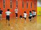 体育館で子供たちがダンスインストラクターの動きをまねてダンスを踊っている。