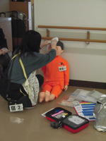 負傷者役の人形に職員がタオルで患部を押さえて止血しているところ