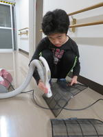 男子舎生が，エアコンフィルターを掃除機を使って埃をとっているところ