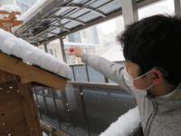 卒業生が作成した小屋の屋根に積もった雪の高さを定規で測っている男子舎生